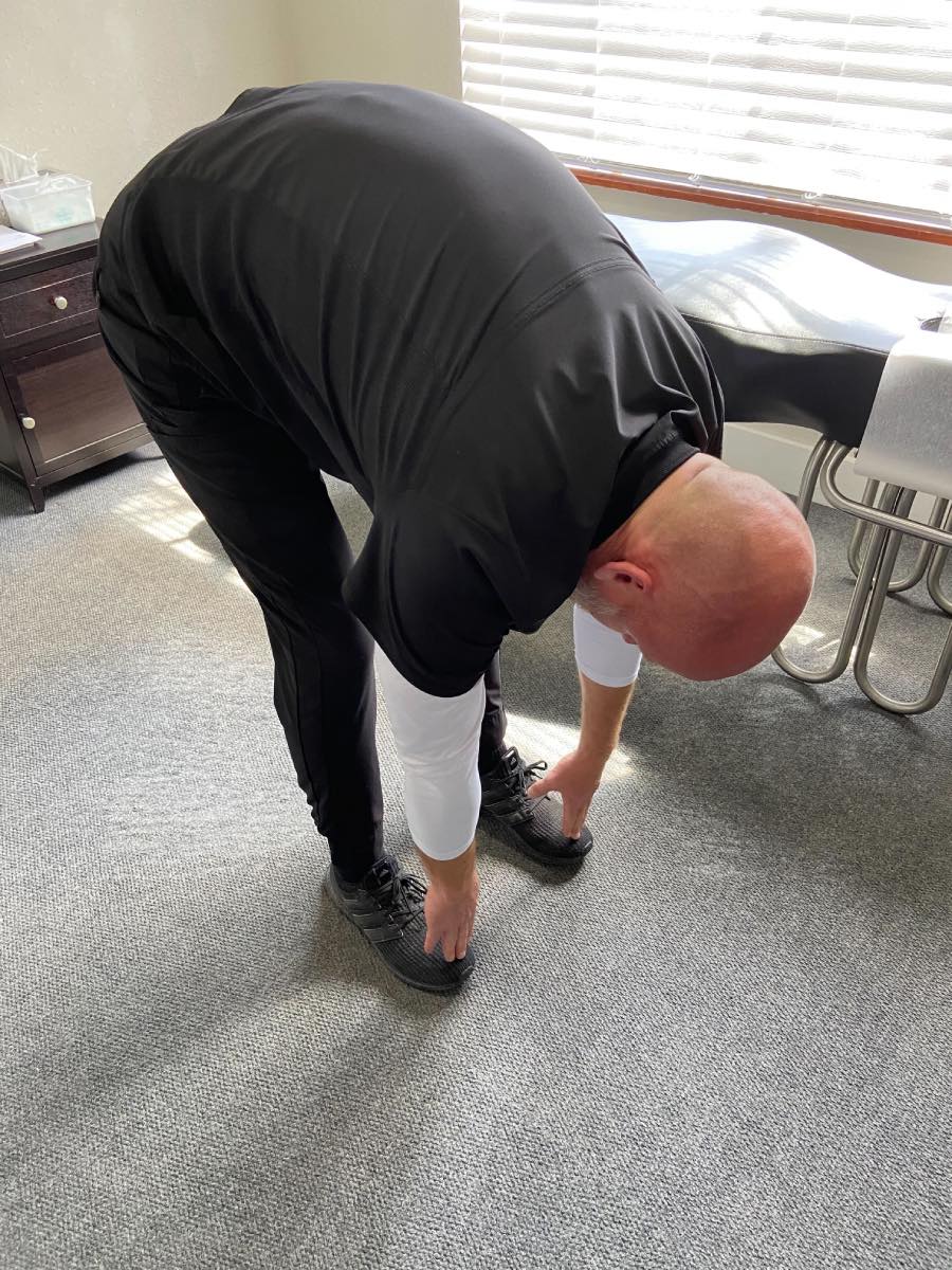 Image of Dr. Daniel Murray: A man bent over touching his hands to his feet.