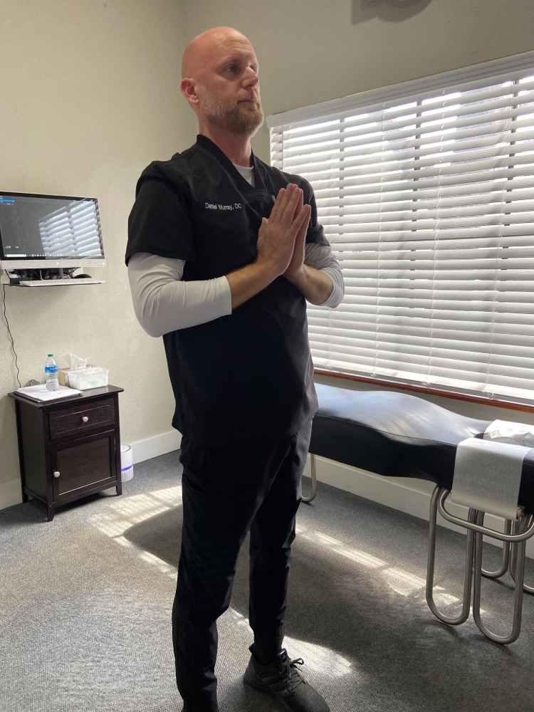 Image of Dr. Daniel Murray: A man is standing up straight, with his hands in a prayer position in the middle of his chest.