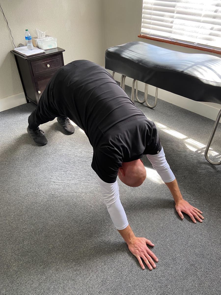 Image of Dr. Daniel Murray: A man in a yoga pose with his hands and feet flat on the ground and his lower torso and hips lifted in the air to make an upside down V shape.