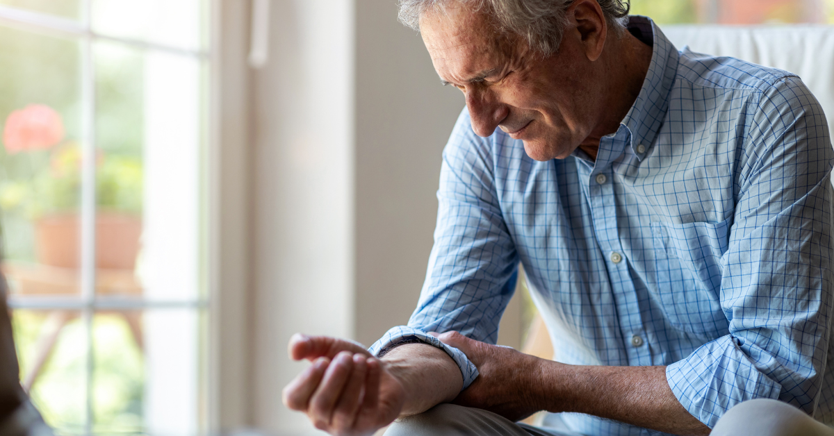 An elderly man is seen holding his elbow in visible pain.